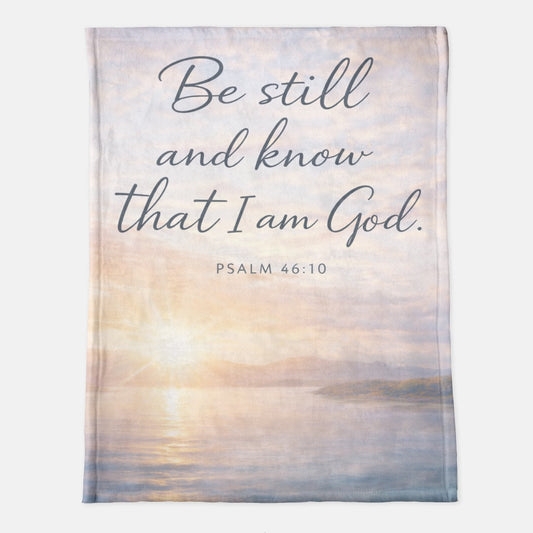 Blanket with sunset design and 'Be still and know that I am God' text on a light background